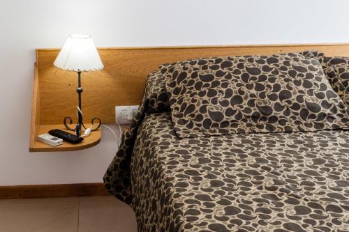 a bedroom with a bed with a lamp on a night stand at El Amparo Hotel in San Luis