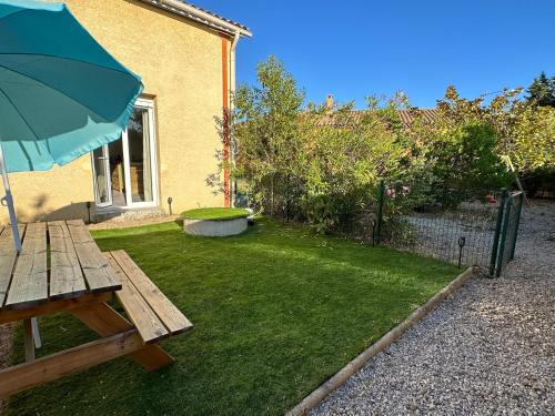 um quintal com uma mesa de piquenique e um guarda-chuva em Studio SPA Balnéo - Jardin privé em Maureilhan-et-Raméjan
