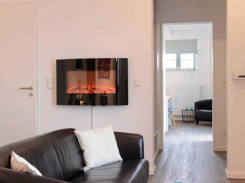 uma sala de estar com um sofá de couro preto e uma lareira em Ohlerich Speicher App_ 19 em Wismar