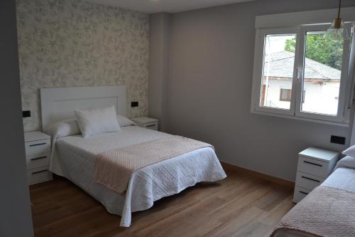a white bedroom with a bed and a window at Inmoinsuas Calle Greco 8 in Sarria