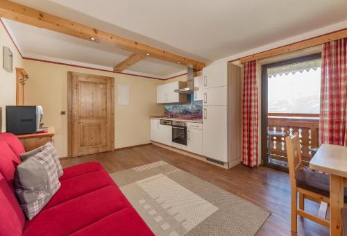 a living room with a red couch and a kitchen at Apparthaus Taxegger in Haus im Ennstal