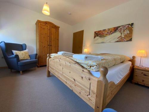 ein Schlafzimmer mit einem großen Bett und einem blauen Stuhl in der Unterkunft Ferienwohnung Heideschmetterling in Hermannsburg