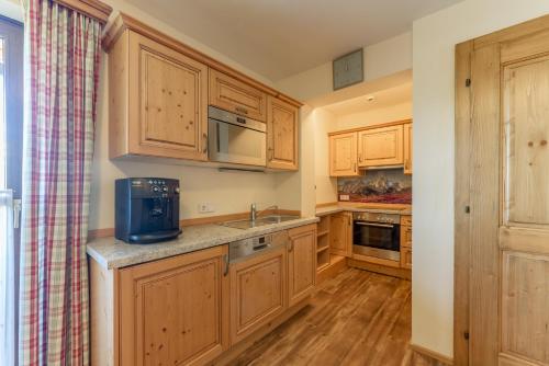 a kitchen with wooden cabinets and a sink and a microwave at Apparthaus Taxegger in Haus im Ennstal
