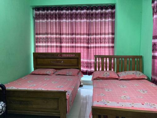 two twin beds in a room with a window at Mohammadia Restaurant & Guest House in Dhaka