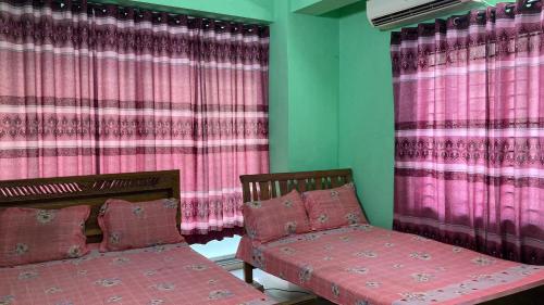 a room with two beds and pink curtains at Mohammadia Restaurant & Guest House in Dhaka