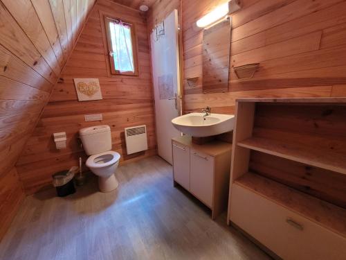 baño con aseo y lavamanos en una cabaña de madera en Camping les Hirondelles, en Bourg-Sainte-Marie