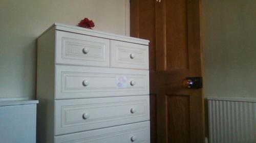 a white dresser with a red bow on top of it at Small but bright single room not far from City Centre in Leicester