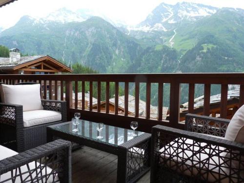 d'un balcon avec une table, des chaises et des montagnes. dans l'établissement Georgette - 3 bedroom apartment in the centre of Sainte Foy, great views, à Sainte-Foy-Tarentaise