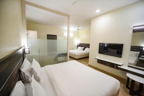 a hotel room with a white bed and a television at Avenue 11 Premium Stays Madurai in Madurai