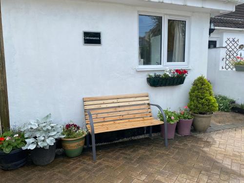 a wooden bench sitting outside of a house with potted plants at 24trenance in Newquay