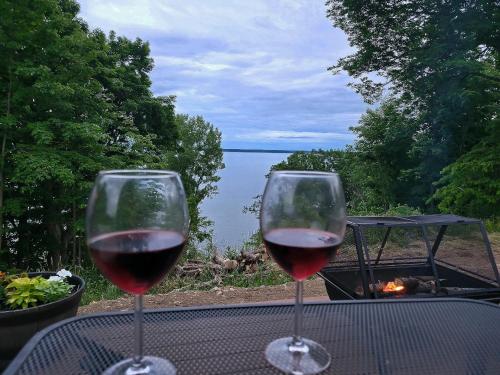 two glasses of wine sitting on a table with a view at Unique waterfront house with private beach in Gananoque