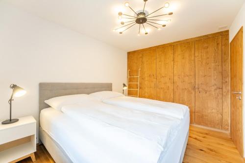 1 dormitorio con cama blanca y lámpara de araña en LAAX Homes Casa Patialas en Sagogn