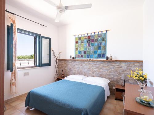 een slaapkamer met een blauw bed en een bakstenen muur bij Casa Vacanze Villa Calathatubi - Locazione turistica breve in Alcamo Marina