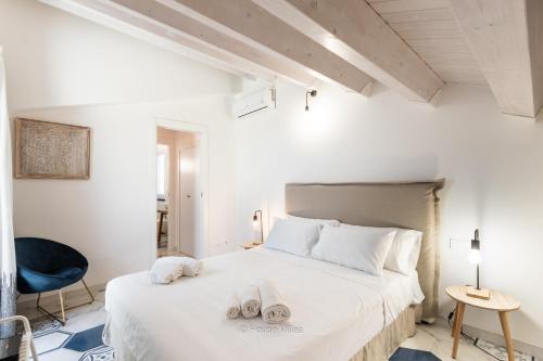 ein Schlafzimmer mit einem großen weißen Bett mit Handtüchern darauf in der Unterkunft House & Villas - Boutique Apartments in Avola