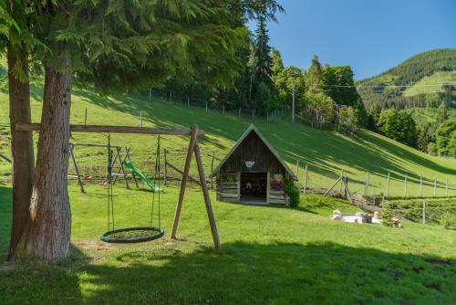 a playground in a field next to a tree at Apparthaus Taxegger in Haus im Ennstal