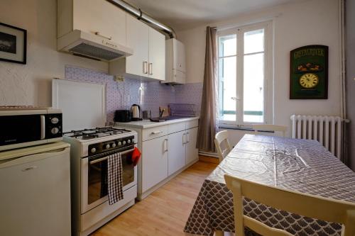 une cuisine avec des placards blancs et une table avec une table dans l'établissement Mon toit carcassonnais •Hypercentre •Terrasse •Vue, à Carcassonne