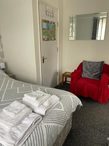 een slaapkamer met een bed en een rode stoel bij 24trenance in Newquay