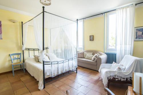 1 dormitorio con cama con dosel y sofá en Volets Bleus et Briques Rouges, en Albi