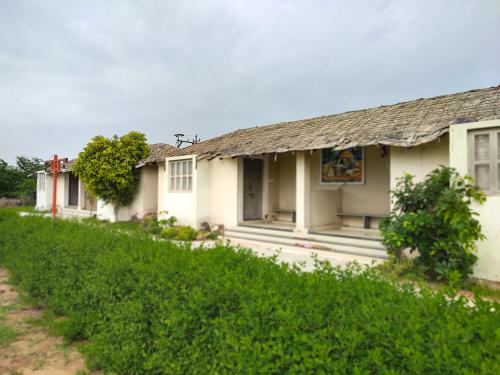 an old white house with a grass roof at River View Resort in Bhuj