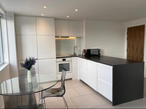 a kitchen with a glass table and white cabinets at Modern and cozy two bed in Clapham 5 in London