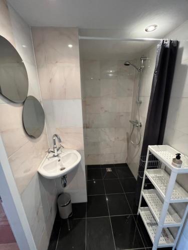 een badkamer met een wastafel en een douche bij Studio J. in Egmond aan Zee