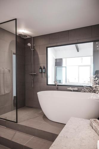 a bathroom with a white tub and a window at Langhoff & Juul Boutique Hotel og Restaurant in Ebeltoft