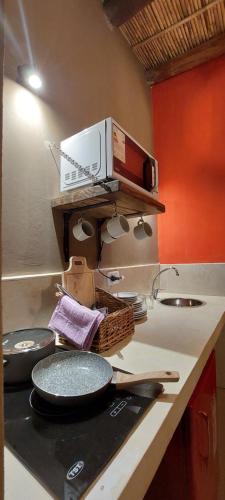 a kitchen with a counter with pans and a microwave at Hotel Tulmas in Tilcara