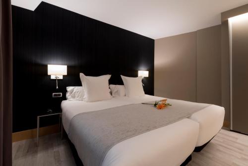 a bedroom with a large white bed with a black wall at Hotel Plaza in A Coruña