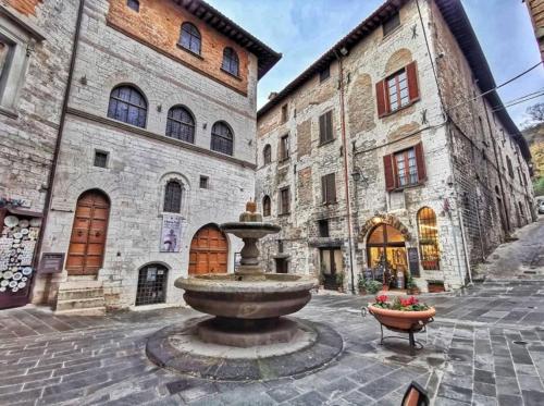 un edificio in pietra con una fontana nel mezzo di un cortile di La Dimora di Pietra a Gubbio