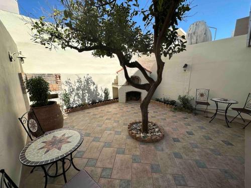 un árbol en un patio con mesa y sillas en SEAmpliCITY cozy apartment, en Heraclión