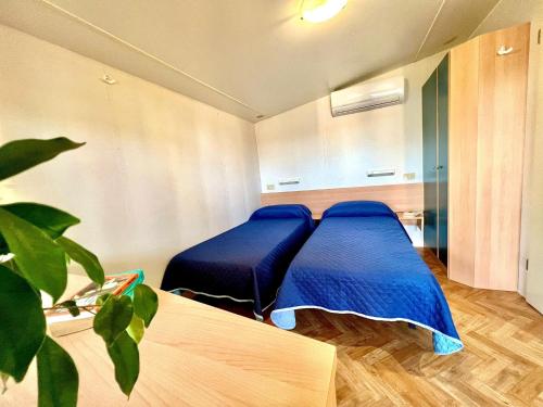 a room with two beds with blue sheets and a plant at Camping Village Tuscia Tirrenica in Tarquinia