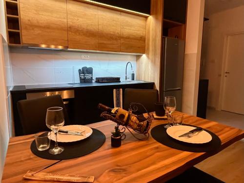 a wooden table with two plates and wine glasses at Apartman Maša in Ruma