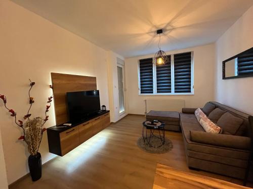 a living room with a couch and a flat screen tv at Apartman Maša in Ruma