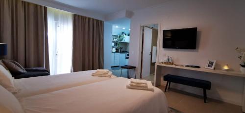 a hotel room with a white bed and a television at Quarto Duplo com Kitchenette, WC e Pátio privativo in Corroios