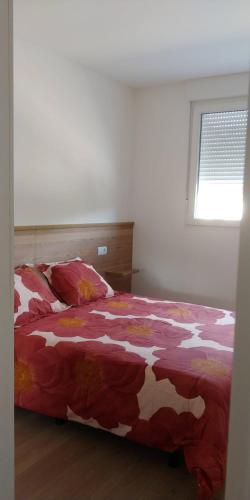 a bedroom with a bed with a red and white comforter at Apartamentos Turísticos Magencio in Carucedo