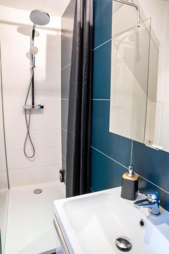 une salle de bain avec un lavabo blanc et un miroir dans l'établissement Les Pétrels by Nid'Ouest - Coeur de ville, à Quimper