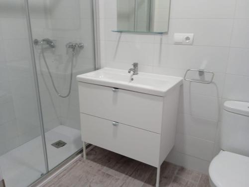 a white bathroom with a sink and a shower at Apartamentos Turísticos Magencio in Carucedo