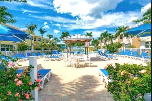 un patio con sillas azules y mesas en una playa en Beach Condo en Clearwater Beach