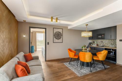 a living room with a couch and a table with orange chairs at Hotel Vinifera Wine & Spa 5 Stars Superior in Balatonfüred