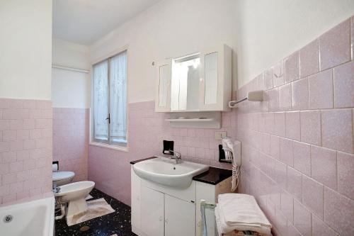 różowa łazienka z umywalką i toaletą w obiekcie Rosina's house w mieście Ventimiglia