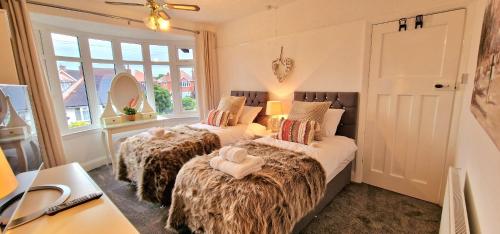 Habitación con 2 camas, ventanas y escritorio. en Beresford Cottage en Skegness