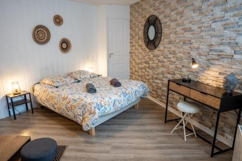 een slaapkamer met een bed en een bakstenen muur bij Les Pétrels by Nid'Ouest - Coeur de ville in Quimper