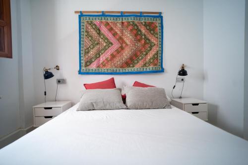 una camera con un letto bianco con due cuscini rossi di Precioso apartamento al lado de la Alhambra a Granada