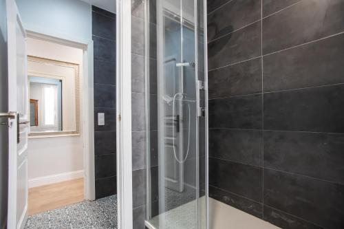 a glass shower in a bathroom with black tiles at Tendency Apartments Miro 6 in Barcelona