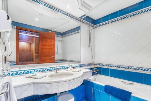 Baño azul y blanco con 2 lavabos y espejo en Best Time Alkantara Djerba, en Djerba