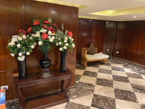 a lobby with two vases of flowers on a table at Executive Royal Tower Apartments - Sky Lounge in El Alamein