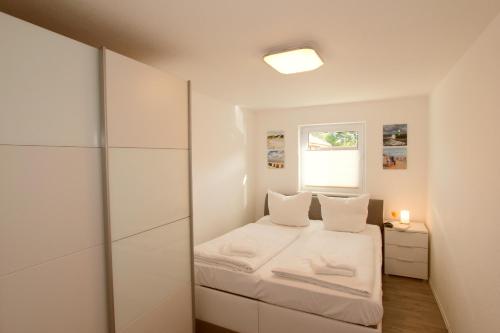 a small white bedroom with a bed and a window at Ferienwohnung Franke in Zinnowitz
