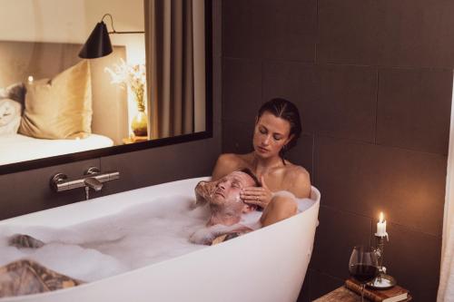 Una donna seduta nella vasca da bagno con un bambino di Langhoff & Juul Boutique Hotel og Restaurant a Ebeltoft