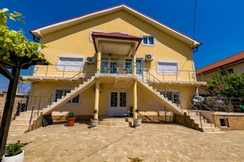 une maison jaune avec des escaliers devant elle dans l'établissement Casa Andrei & Alex 2 Mai, à 2 Mai