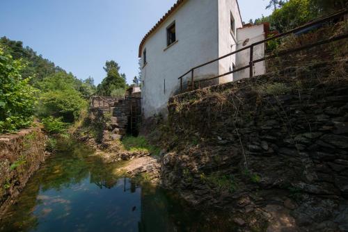 a building on the side of a hill next to a river at Encosta da serra do Bussaco Quintinha da Azenha in Penacova